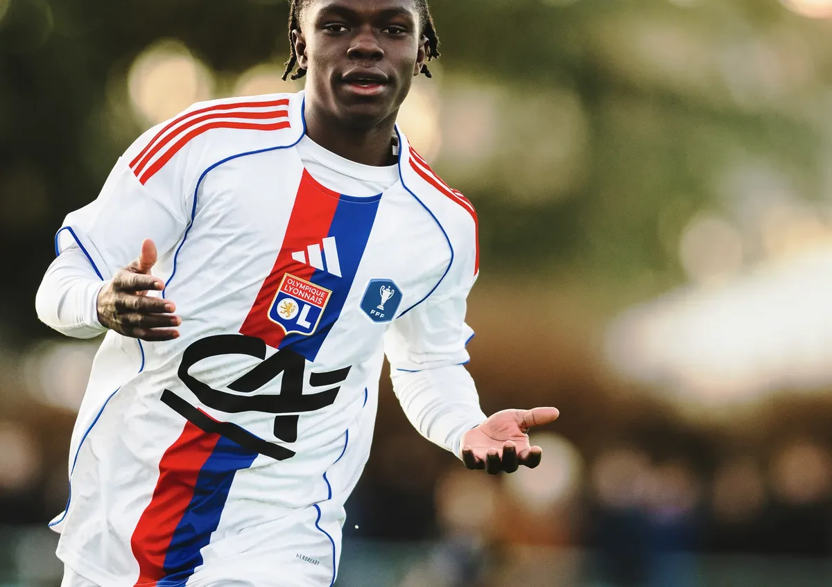 Jeune joueur de l'Olympique Lyonnais, bras ouverts sur le terrain